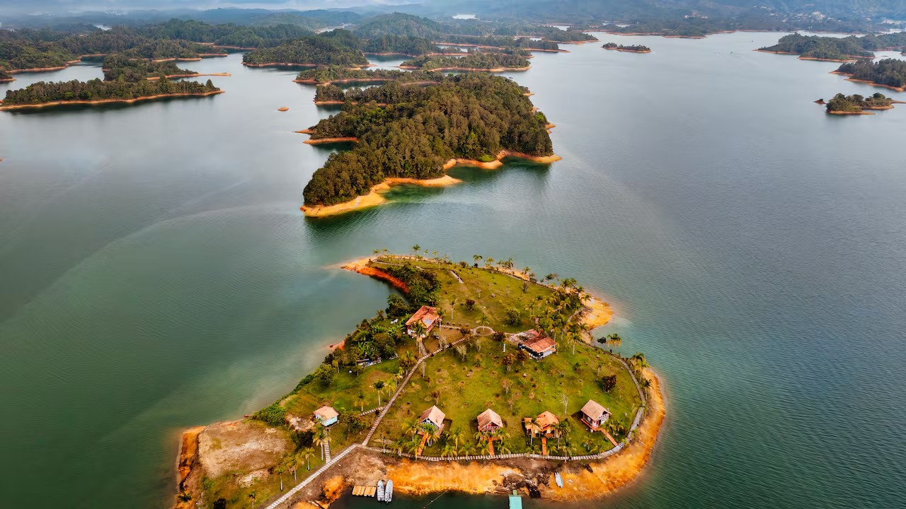 Isla de la Fantasía en Guatapé vista desde el agua, con cabañas y palmeras